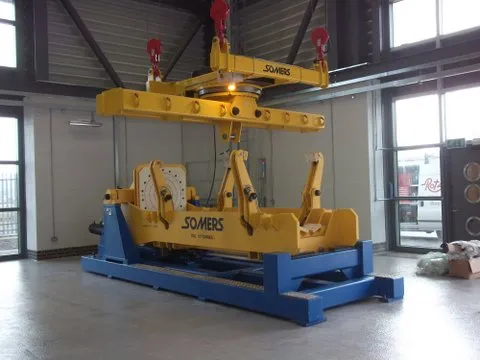 Somers-branded bespoke turnover manipulator — yellow and blue steel frame with twin end bearings on a fabrication shop floor.