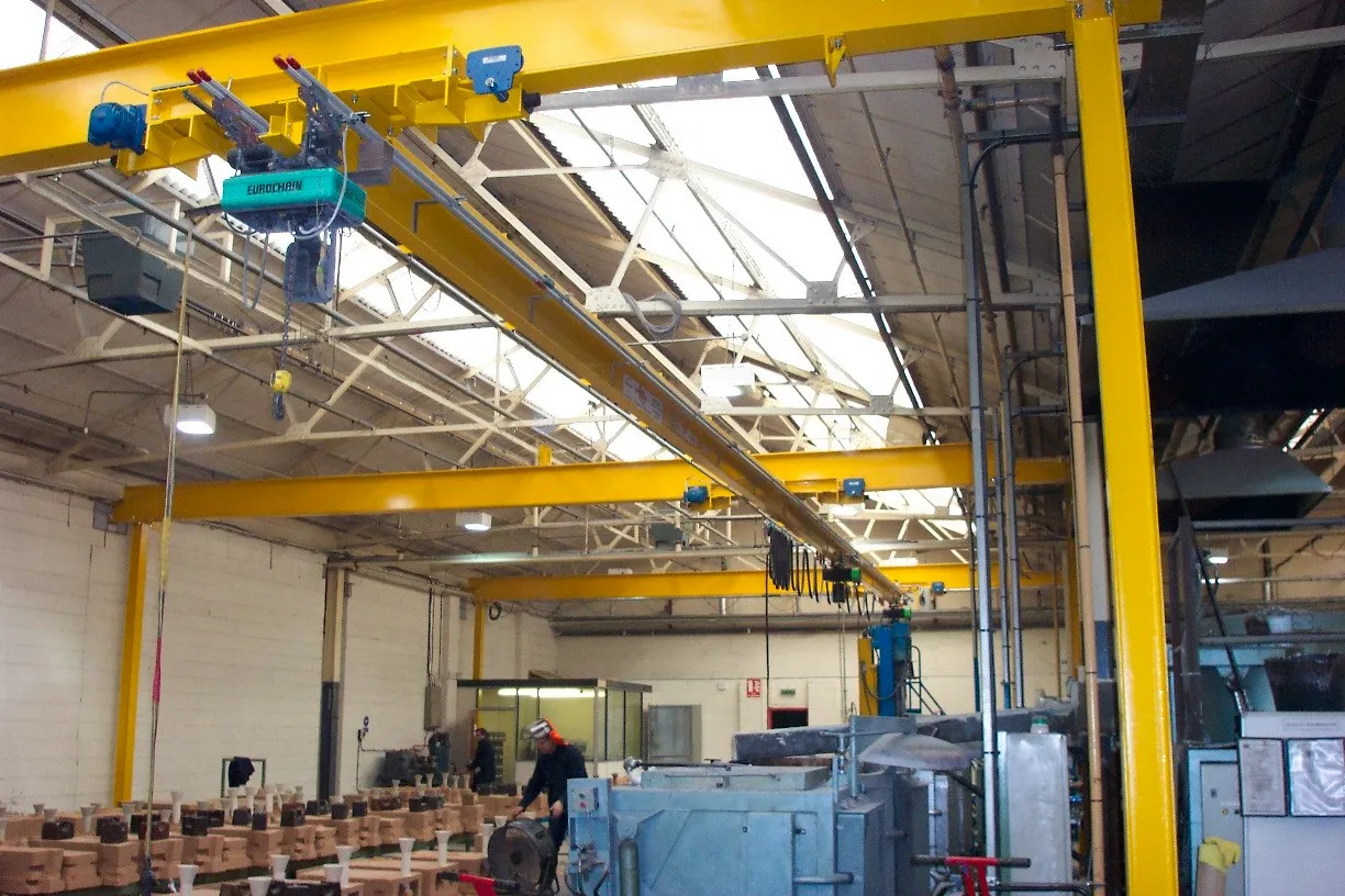 Somers yellow overhead crane and branched monorail runway above a production workshop, with electric chain hoists suspended.