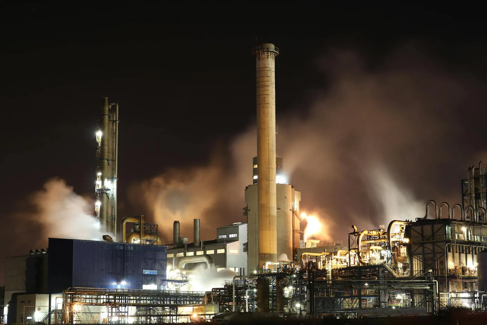 Industrial plant at night with illuminated stacks and pipework — TODO replace with real Somers hot-line photography.