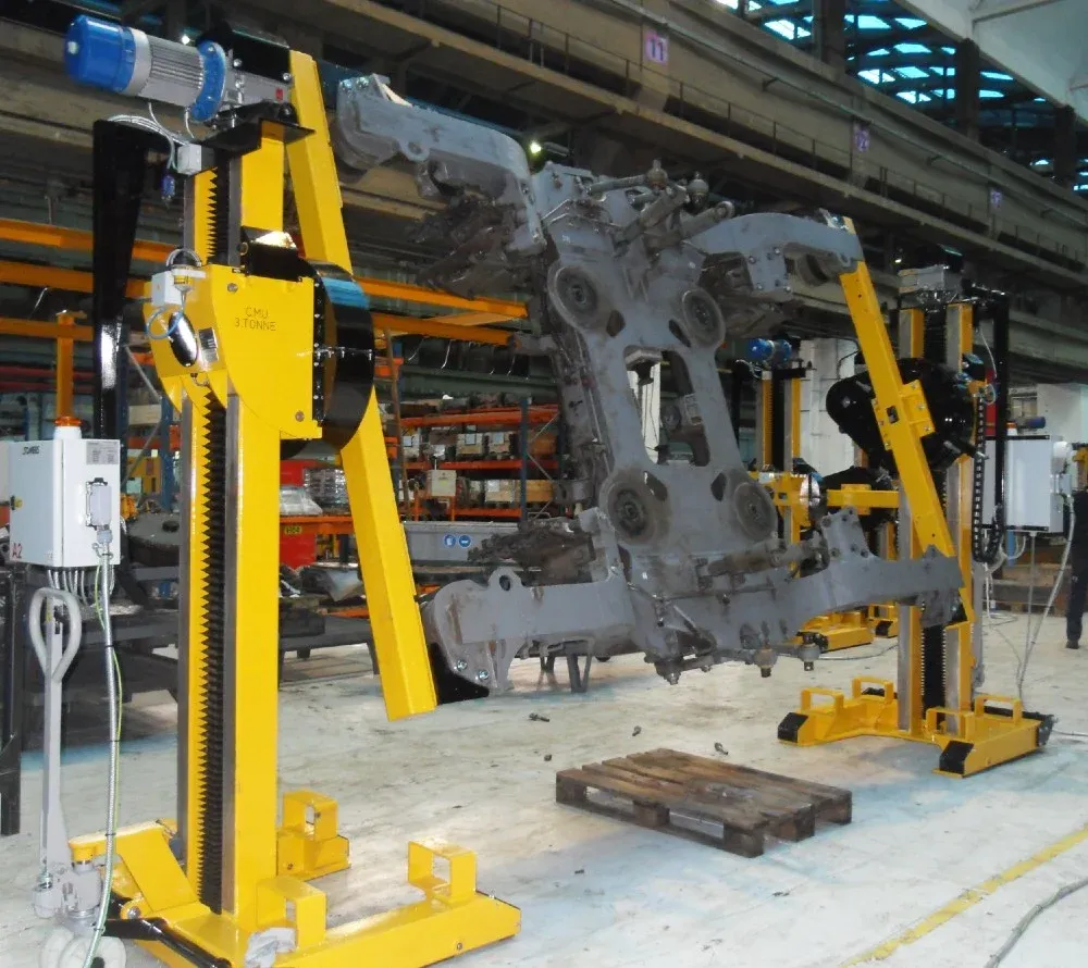 Somers bogie rotator with yellow rack-driven columns supporting a railway bogie frame in a maintenance workshop.