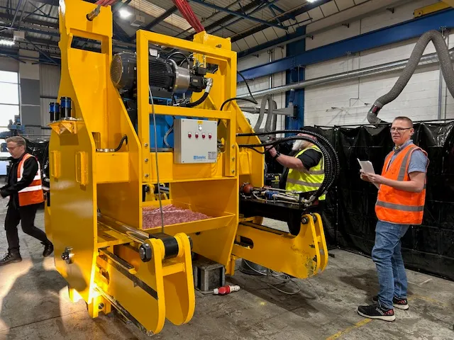 Somers engineers in hi-vis completing a Factory Acceptance Test on a yellow hydraulic billet tong in the Wednesbury works, with the customer representative observing.